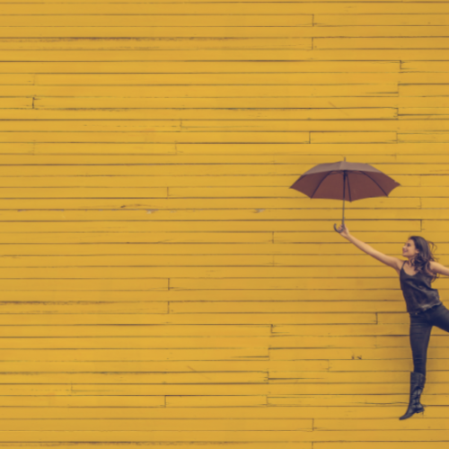黄色い壁と傘を持つ女性
