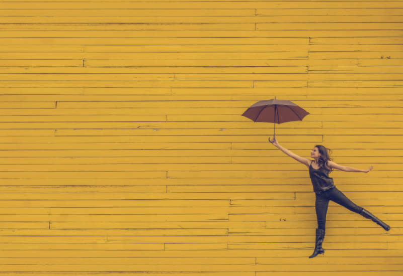 黄色い壁と傘を持つ女性